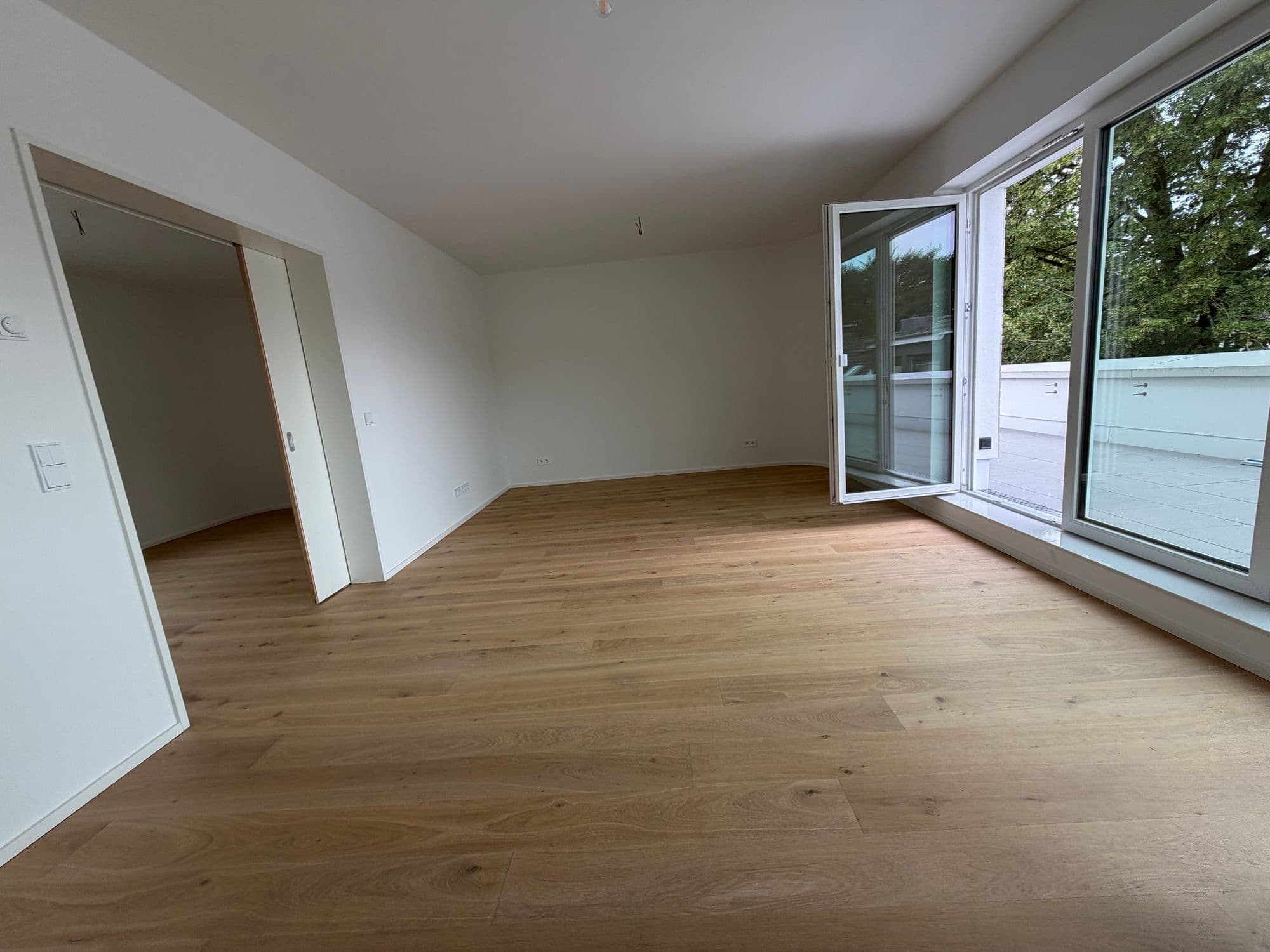 Wohnraum mit Eck-Verglasung und offener Tür zur Dachterrasse